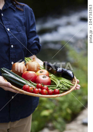 川の前で採れたての野菜をもつ農家の日本人女性 104738363