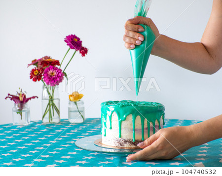hands level the cream with a pastry bag and cover the round cake hands level the cream with a pastry bag and cover the round cake 104740532