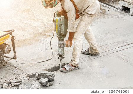 Construction worker using jackhammer drilling concrete surface Construction worker using jackhammer drilling concrete surface 104741005
