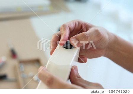 Asian man assembling furniture at home with adjustable table leg Asian man assembling furniture at home with adjustable table leg 104741020