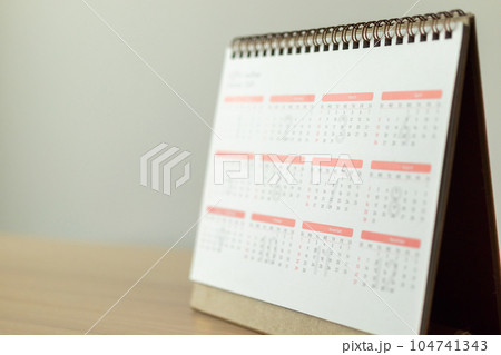 Calendar page close up on wood table with white wall background business planning appointment meeting concept Calendar page close up on wood table with white wall background business planning appointment meeting concept 104741343