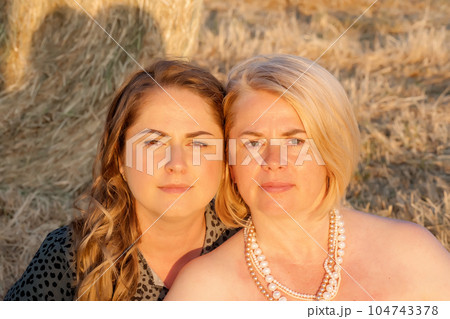 Portrait of adult sisters in nature against a background of hay. Family values. 104743378
