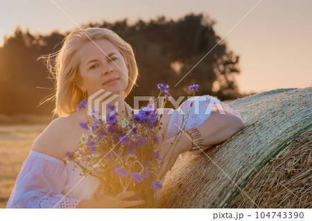 Portrait of attractive young woman in retro dress with a bouquet of wildflowers in countryside. Portrait of attractive young woman in retro dress with a bouquet of wildflowers in countryside. 104743390