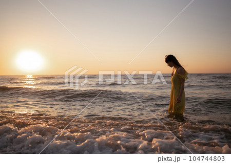 Young woman walks along seashore at sunset. Nature, relax, lifestyle concept. 104744803