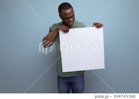 positive young smart american man in t-shirt showing white screen with mockup for information 104745360