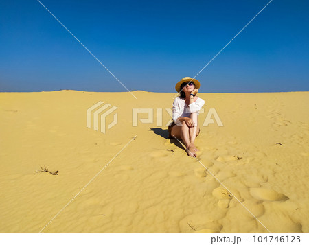 Young woman in white blouse and brown shorts walking in desert Young woman in white blouse and brown shorts walking in desert 104746123