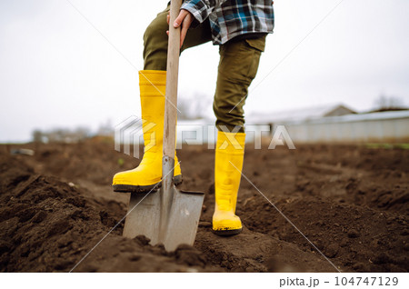 Female Worker digs soil with shovel in the vegetable garden. Agriculture and tough work concept 104747129