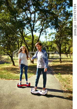 Young man and woman riding on the Hoverboard in the park. content technologies. a new movement. 104747494