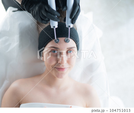 Young caucasian woman on microcurrent therapy procedure. Beautician's office. 104751013