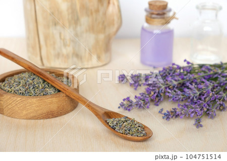 Dry lavender flowers in wooden bowl and bottle of essential lavender oil or infused water on white background. Natural organic ingredients for herbal cosmetics. Spa massage set, lavender product 104751514