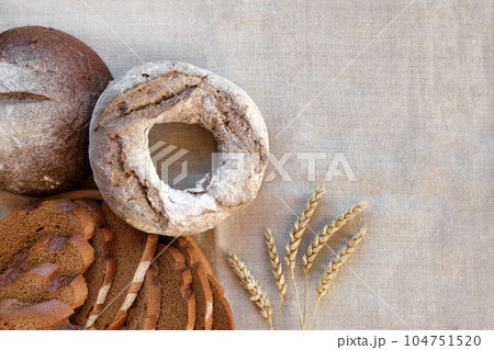 Baked bread. Loaf of Bread. Fresh Bakery Products on Wooden Board. Healthy Food Concept. Top View. Flat lay. Slices of Homemade Sourdough Bread with Flour on Rustic Linen Background. Wheat Spikes Baked bread. Loaf of Bread. Fresh Bakery Products on Wooden Board. Healthy Food Concept. Top View. Flat lay. Slices of Homemade Sourdough Bread with Flour on Rustic Linen Background. Wheat Spikes 104751520