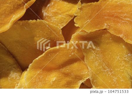Dried mango slices close-up on a white. Top view. Closeup. Mango chips background. Dehydrated crispy fruit slices, pieces. Heap of sun-dried yellow fruit. Healthy meal. Top view, flat lay 104751533