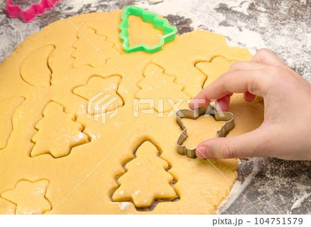 Kids hand with form of christmas cookies for children, making gingerbread in form of man. New year treat for Santa Claus cooking. Raw dough. Homemade bakery, xmas sweet, winter holidays concept 104751579