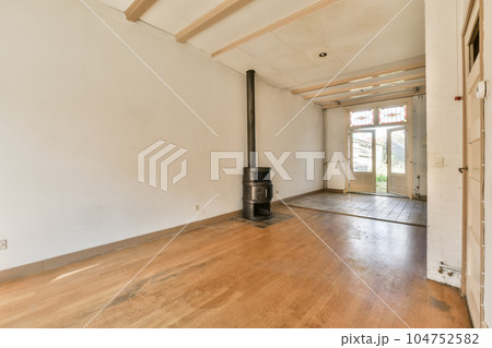 an empty living room with wood flooring and a wood burning stove in the middle part of the room is white walls an empty living room with wood flooring and a wood burning stove in the middle part of the room is white walls 104752582