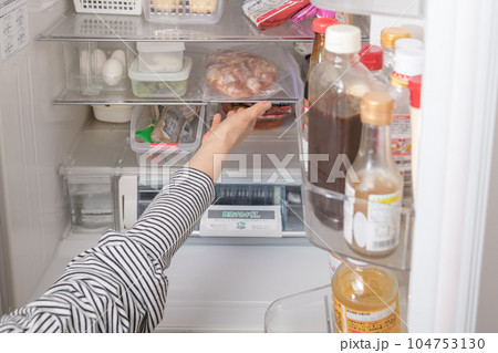 【冷蔵室から唐揚用の下味を付けた鶏肉を出す主婦】 104753130