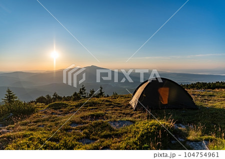 Tent at the peak in the mountains during sunrise. The sun rises over Babia Gora Tent at the peak in the mountains during sunrise. The sun rises over Babia Gora 104754961