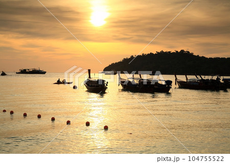 Silhouette people kayak by boats on sea at sunset, Ko Lipe island Silhouette people kayak by boats on sea at sunset, Ko Lipe island 104755522