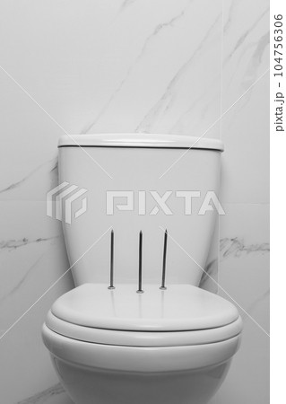 Toilet bowl with nails near marble wall. Hemorrhoids concept 104756306