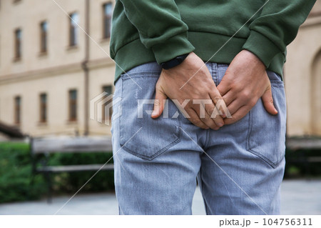 Man suffering from hemorrhoid pain outdoors, back view Man suffering from hemorrhoid pain outdoors, back view 104756311