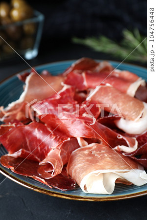 Tasty fresh prosciutto on black table, closeup Tasty fresh prosciutto on black table, closeup 104756448