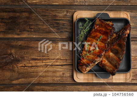 Tasty grilled ribs on wooden table, top view. Space for text Tasty grilled ribs on wooden table, top view. Space for text 104756560