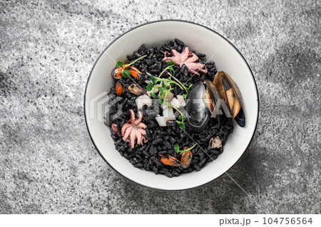 Delicious black risotto with seafood in bowl on light grey table, top view 104756564