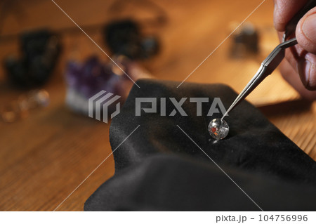 Professional jeweler working with beautiful gemstone at table, closeup Professional jeweler working with beautiful gemstone at table, closeup 104756996