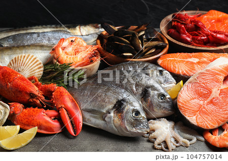 Fresh raw fish and different seafood on grey table Fresh raw fish and different seafood on grey table 104757014