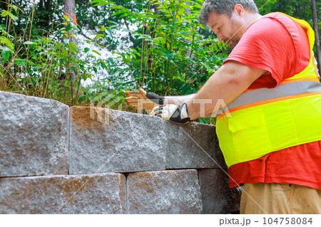 With precision skill construction worker attached concrete block securely to retaining wall. With precision skill construction worker attached concrete block securely to retaining wall. 104758084