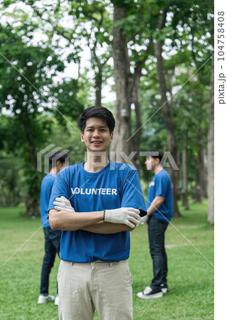 Volunteering, charity and clean environment concept. Happy man and group of volunteers with garbage bags cleaning area in park, copy space 104758408