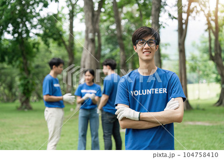 Volunteering, charity and clean environment concept. Happy man and group of volunteers with garbage bags cleaning area in park, copy space 104758410