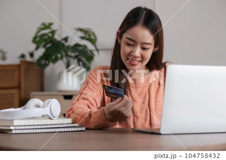 Image of young asian woman order online, shopping from home. Girl enter credit card info on webside to make purchase, using laptop to shop, paying bills with computer Image of young asian woman order online, shopping from home. Girl enter credit card info on webside to make purchase, using laptop to shop, paying bills with computer 104758432