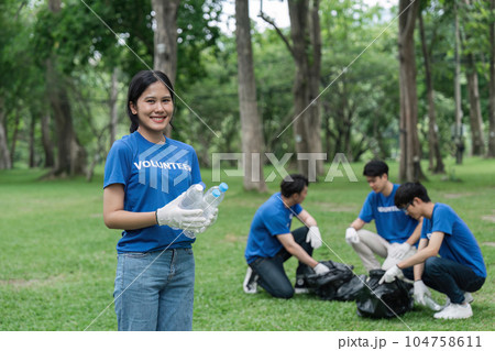 Pretty smiling female collecting forest garbage, looking at camera, volunteering Pretty smiling female collecting forest garbage, looking at camera, volunteering 104758611
