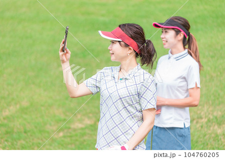 ゴルフ場でスマホを使って動画を撮ってスイングの確認をするゴルファーの女性 104760205