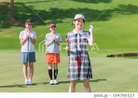ゴルフ場のグリーンでゴルフをするゴルファーの女性(パター) 104760323