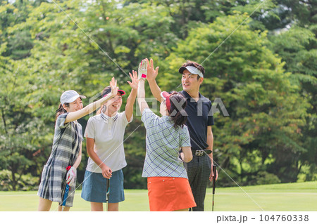 ゴルフ場でハイタッチするゴルフ仲間の男女 104760338