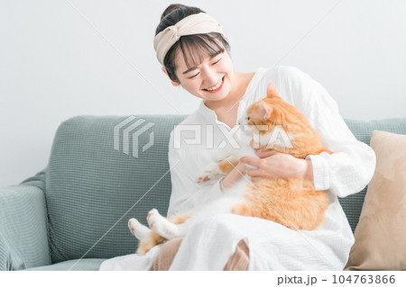 家で猫を抱っこする日本人女性（ペット・飼い主） 104763866