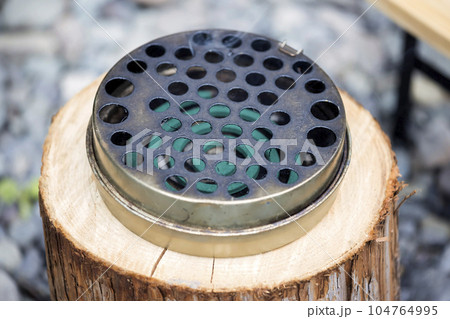 屋外で蚊取り線香を蚊取り線香入れに入れて使うイメージ 104764995