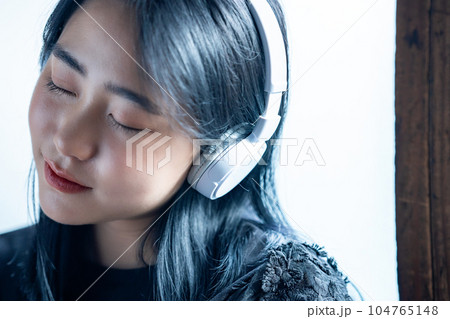 ヘッドホンで音楽を聴く若い女性 104765148