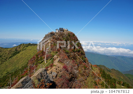 青空を背景に紅葉色づく石鎚山天狗岳から見た弥山 104767812