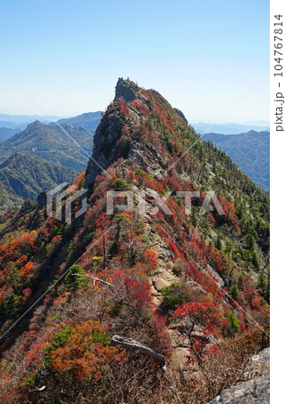 秋晴れの青空を背景に紅葉に染まる石鎚山天狗岳 Ver2 104767814