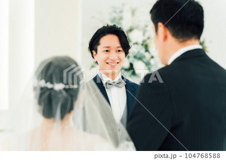 結婚式場・チャペルでバージンロードを歩く新婦を待つ新郎・花婿の男性 104768588