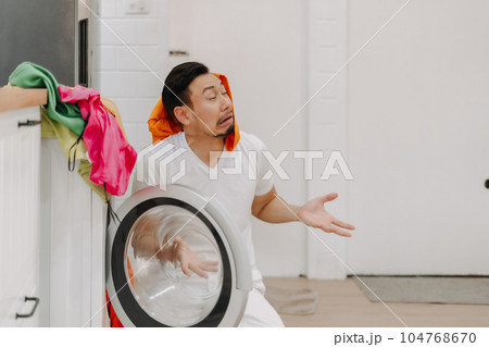 Funny crying man husband thrown with pile of clothes on his face to be washed. Funny crying man husband thrown with pile of clothes on his face to be washed. 104768670