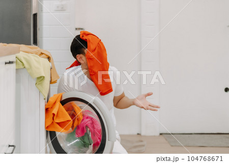 Funny crying man husband thrown with pile of clothes on his face to be washed. Funny crying man husband thrown with pile of clothes on his face to be washed. 104768671