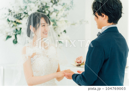 教会・チャペルで向かい合って誓いを立てる新郎新婦（ウェディング・ブライダル） 104769003