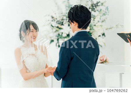 教会・チャペルで向かい合って誓いを立てる新郎新婦（ウェディング・ブライダル） 104769262