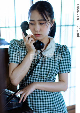 黒電話を使う若い女性 104770904
