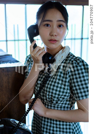 黒電話を使う若い女性 104770907