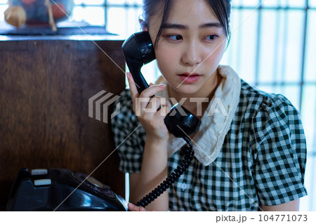 黒電話を使う若い女性 104771073