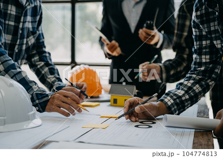 Working as a team architect and designer working on blueprint project of new apartments. Photo concept of work on technical drawings in office. 104774813